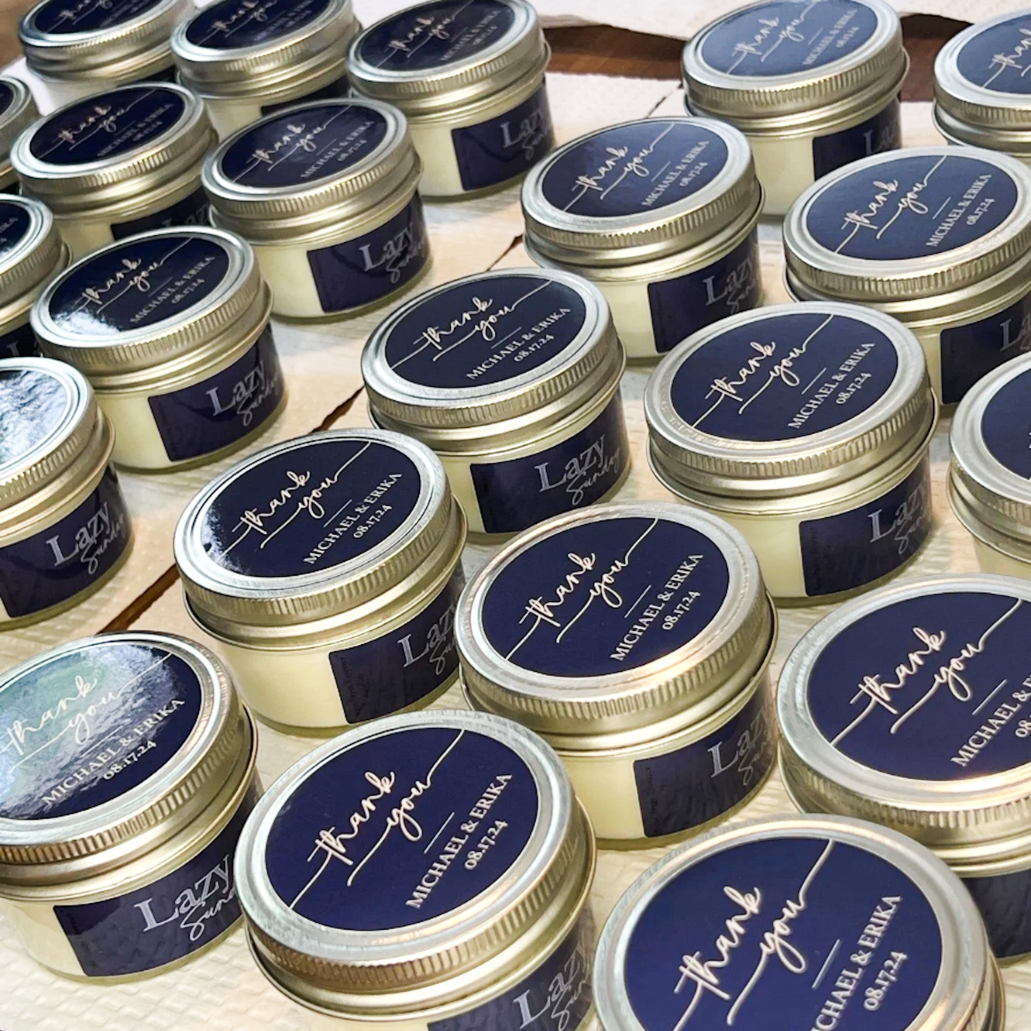 Wedding favor candle tins labeled “thank you” with couple's names and wedding date
